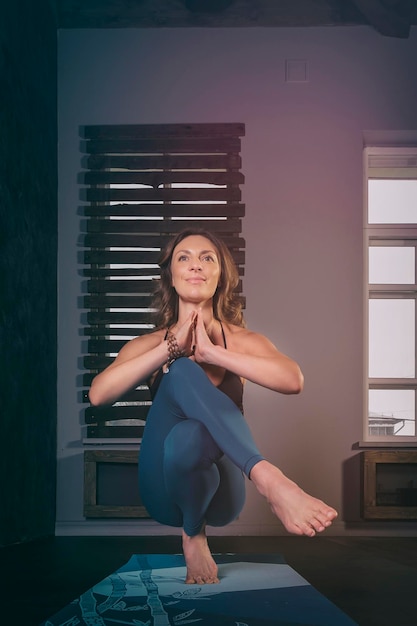 a charming girl in a sports uniform does yoga in an old room with a fireplace and candles