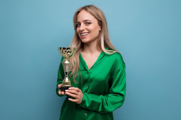 Ragazza affascinante con una coppa del campionato su uno sfondo blu brillante