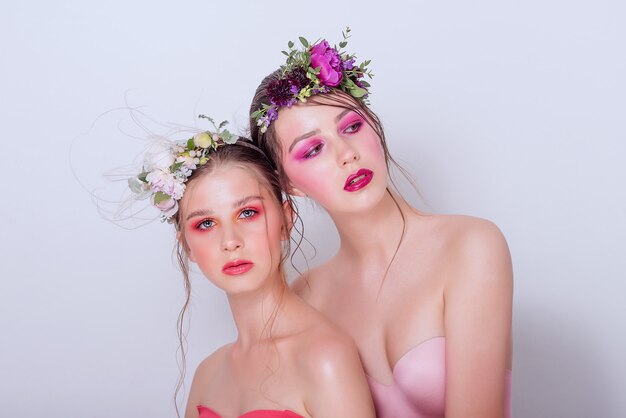 Ragazze affascinanti con trucco alla moda e audace e fiori freschi