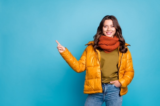 Charming lady point finger at copy space on blue wall