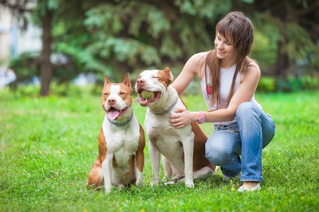 魅力的な女性が屋外の犬と一緒にポーズします。