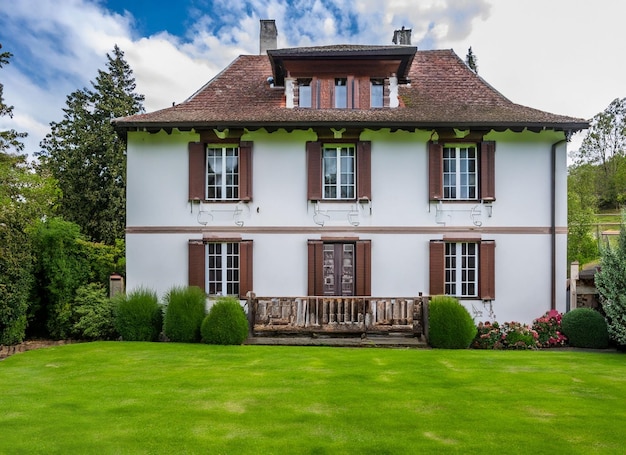 Charming light yellow house with wooden windows and a green grassy garden