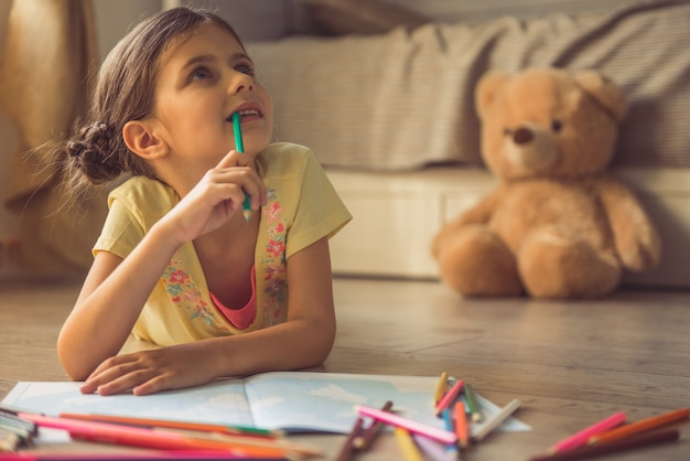 Charming little girl is drawing, looking away.