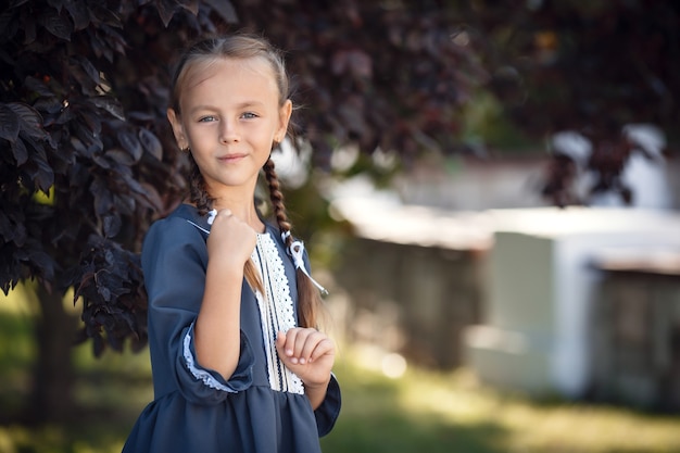 Charming little girl in a retro dress walking in the city on a sunny summer day. Little girl wear school uniform. 