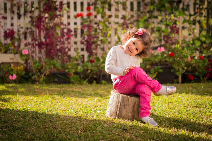 Charming little girl sitted on backyard in pink pants