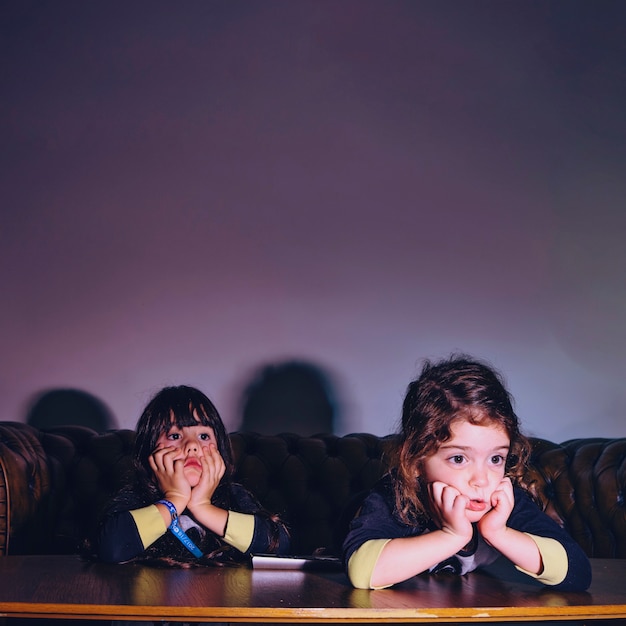 Photo charming little girls watching movie