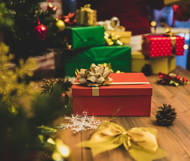 겨울 축하 파티를 위해 크리스마스 트리를 장식하기 위한 나무 탁자, 눈송이, 소나무 콘에 있는 매력적인 고급 선물 상자와 아름다운 활. 빈티지 스타일 이미지에 맞게 약간의 노이즈 추가