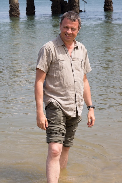 Charming man barefoot at the beach on holidays