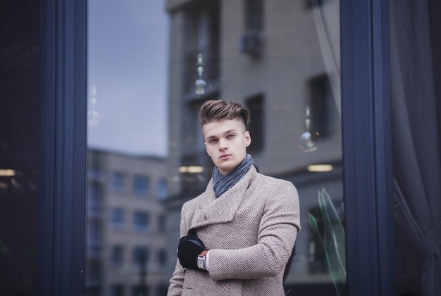 Charming man. Handsome young man in coat in city