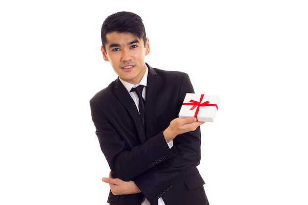 Charming man with black hair in white shirt and black suit with tie holding a present