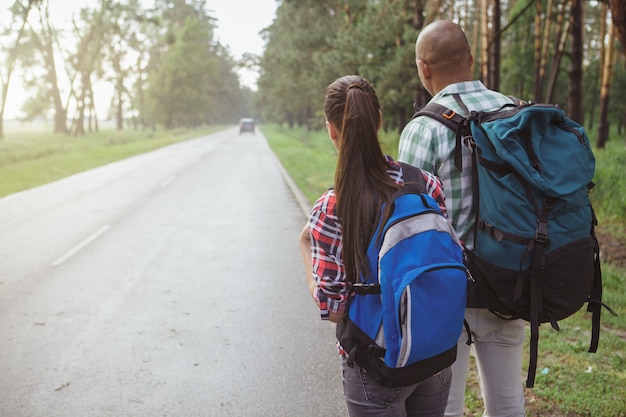 Charming multiracial couple hitchhiking together