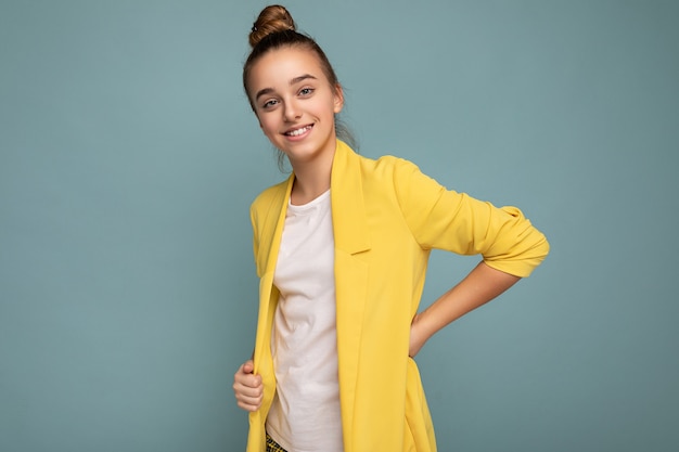 charming positive happy smiling brunette little female teenager wearing trendy yellow jacket and white t-shirt standing isolated 