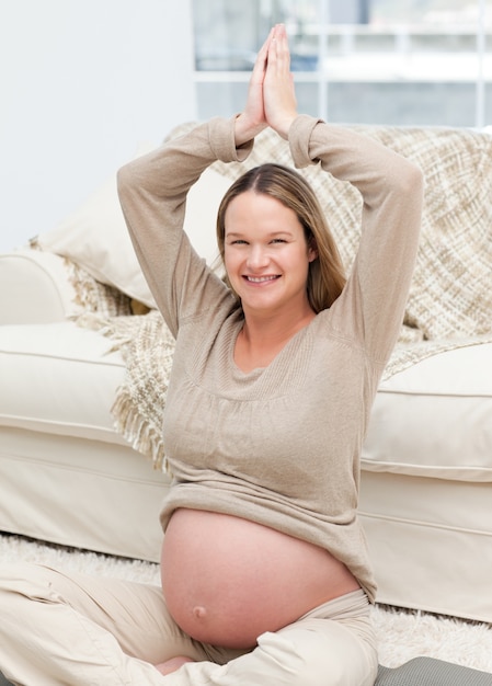 Foto affascinante donna incinta facendo esercizi di yoga sul pavimento