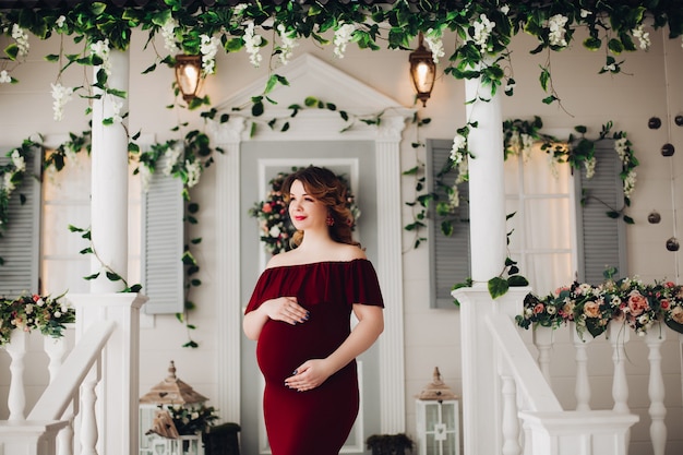 Charming pregnant woman in marsala dress posing