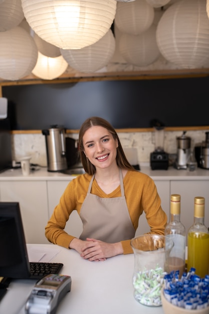 A charming and smiling barista standing at the counter