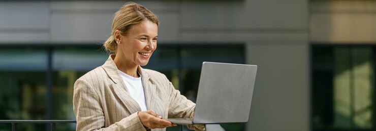 Charming smiling business woman working laptop while standing on modern office terrace