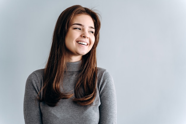 Charming, smiling girl on a gray