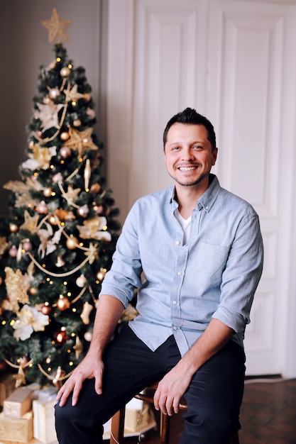 クリスマスツリーの横にある魅力的な笑みを浮かべて男
