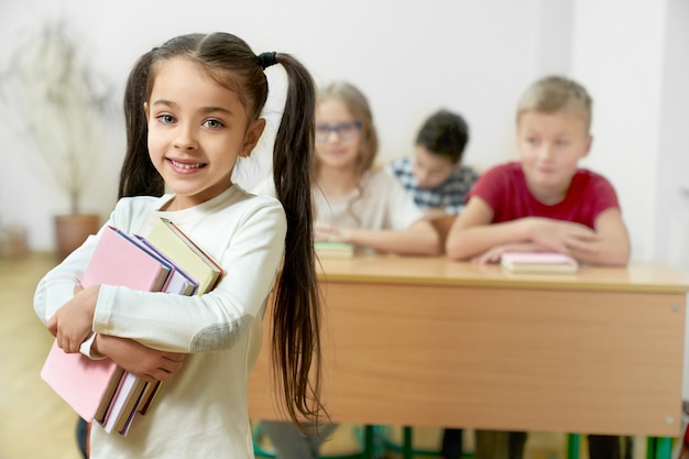 Charming student keeping several books in hands and posing