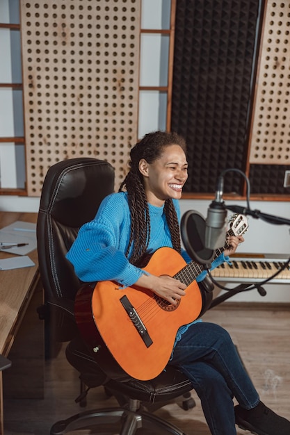 写真 魅力的な才能のあるアフリカの若い女性ミュージシャン ソング ライターの歌手がギターを弾き、音楽スタジオで新しい曲を録音します。