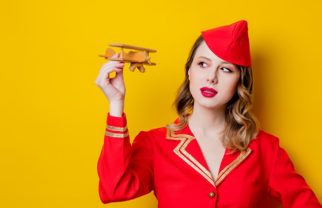 charming vintage stewardess wearing in red uniform with airplane