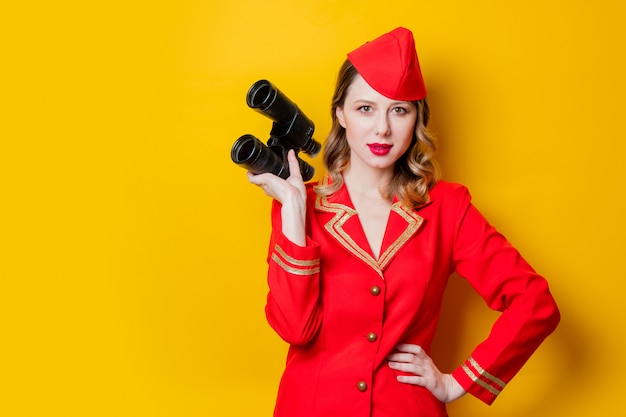 Affascinante hostess vintage che indossa in uniforme rossa con binocolo