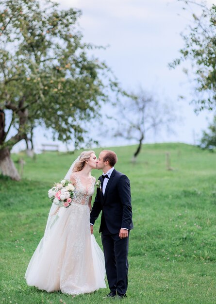 Charming wedding couple walks around in a green summer garden