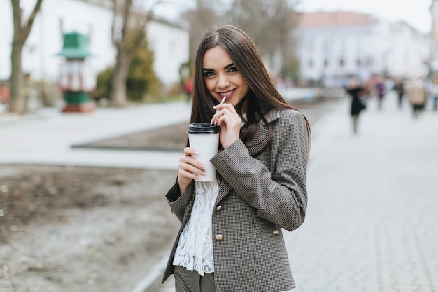 Charming woman enjoying milkshake on street