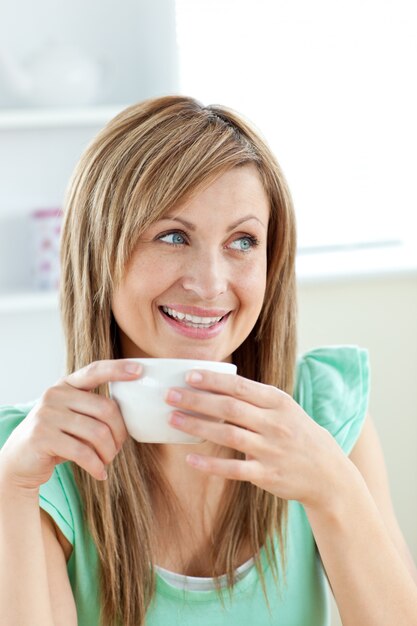 Charming woman holding a cup of coffee sitting in the ktichen