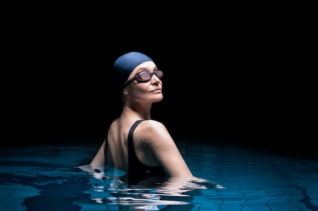 Charming woman posing in the pool. Back view.