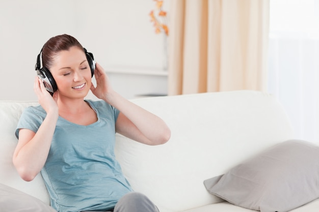 Charming woman relaxing with headphones while sitting on a sofa