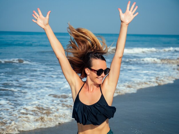 Charming woman runs to meet friends on the beach