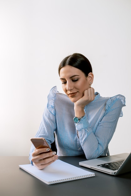 Charming woman using smartphone at office desk.