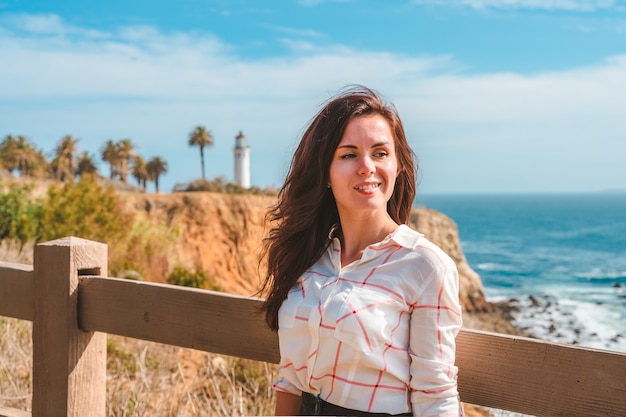 A charming woman walks along waterfront with a view of the Point Vicente Lighthouse In Los Angeles