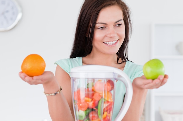 Charming woman with a blender and fruits