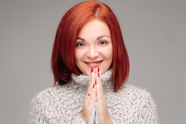 Charming woman with ginger hair smiling and putting hands together