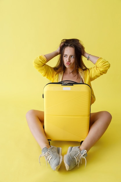 Charming woman with travel bag sitting in studio