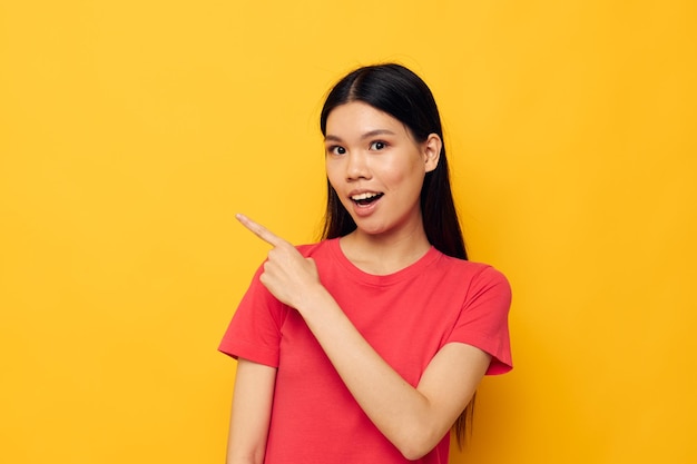 Charming young asian woman gestures with her hands in casual clothes copyspace yellow background una