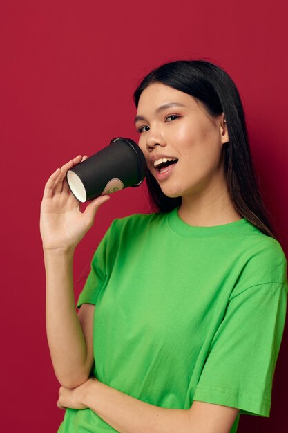 Charming young Asian woman in a green tshirt a glass of drink fun studio model unaltered