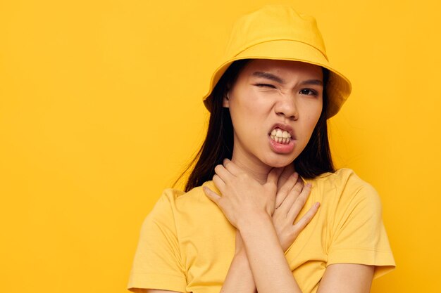 Charming young asian woman wearing a yellow hat posing emotions yellow background unaltered person