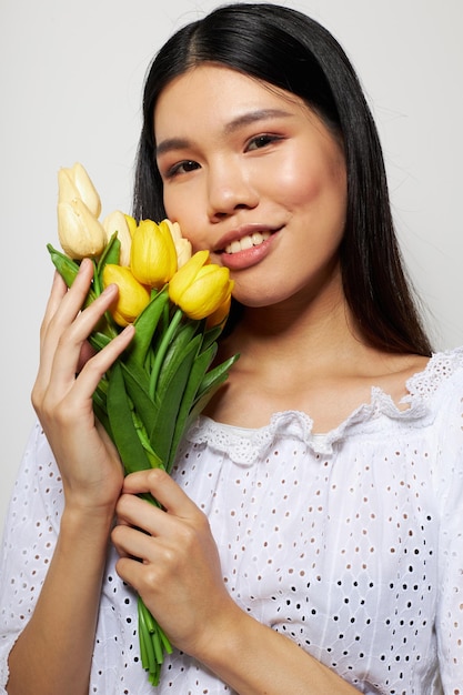 Charming young Asian woman in a white shirt flowers spring posing studio model unaltered. High quality photo