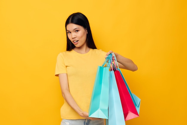 Charming young Asian woman with packages in hands shopping isolated background unaltered