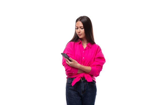 Photo charming young brunette businesswoman dressed in a pink shirt is chatting in a smartphone