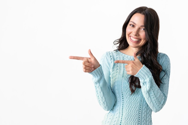 Photo charming young brunette woman points to copy space a delightful whitetoothed smile