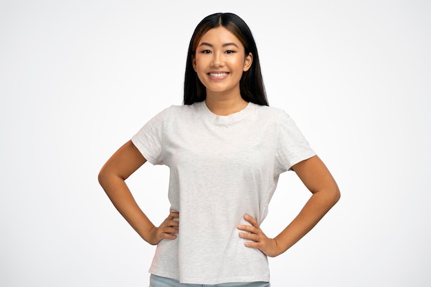 Charming young brunette woman stands with arms on the waist and looks at the camera