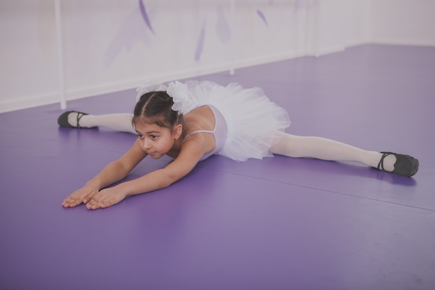Charming young girl ballerina exercising at dance school