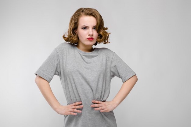 Charming young girl in a gray T-shirt. The girl put her hands on her waist