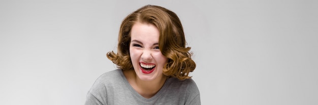 Photo charming young girl in a gray t-shirt on a gray background. the girl leads a dialogue