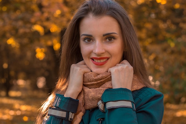 A charming young girl with red lipstick on lips holding hands and smiling scarf closeup