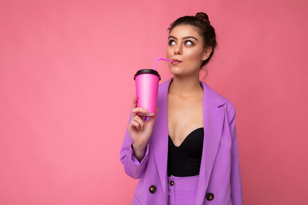 Charming young happy thoughtful brunette woman wearing stylish clothes isolated over colourful